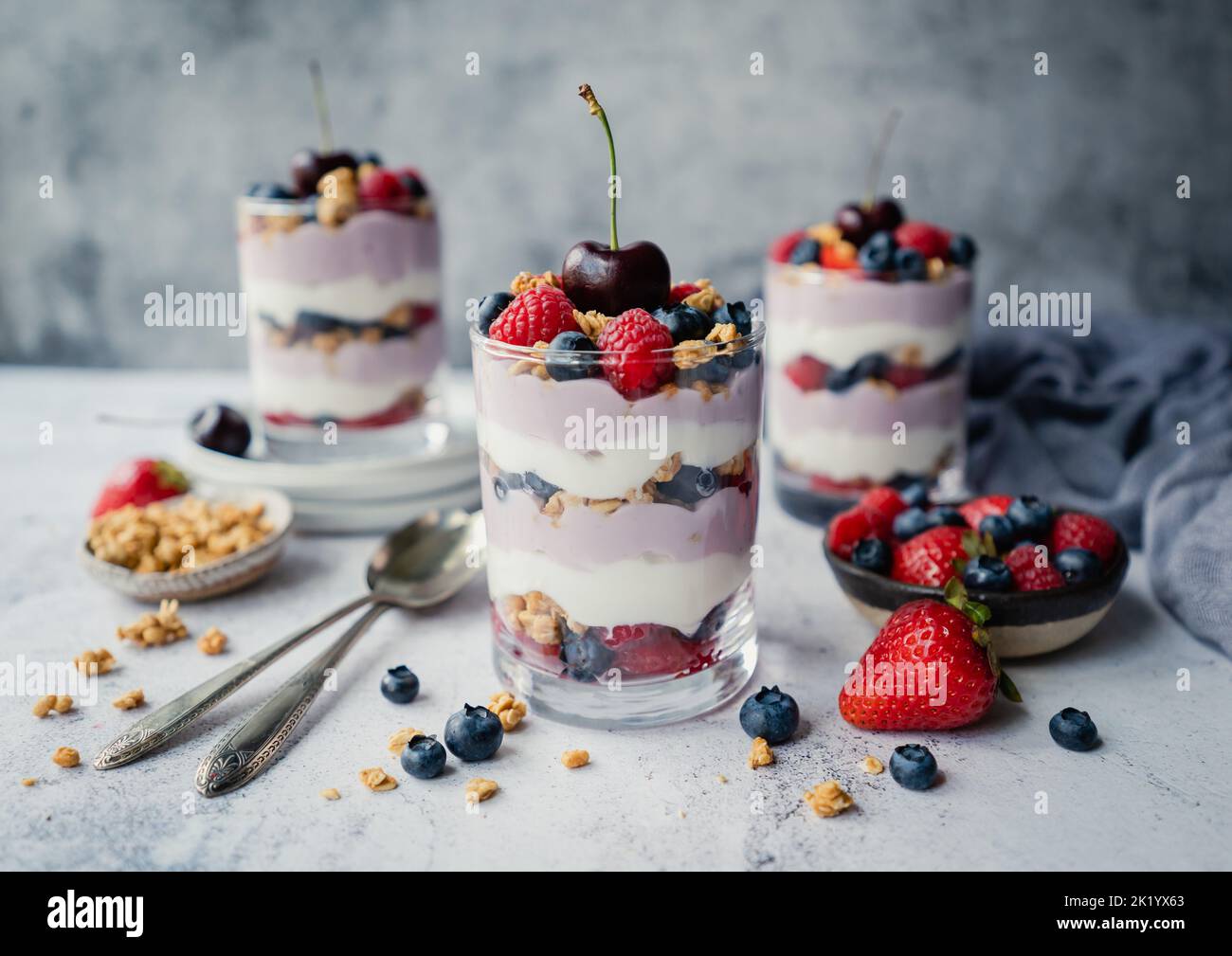 Nahaufnahme von gemischten Beerenjoghurt-Parfaits auf grauem Hintergrund. Stockfoto