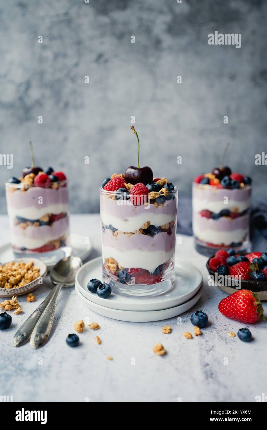 Nahaufnahme von gemischten Beerenjoghurt-Parfaits auf grauem Hintergrund. Stockfoto