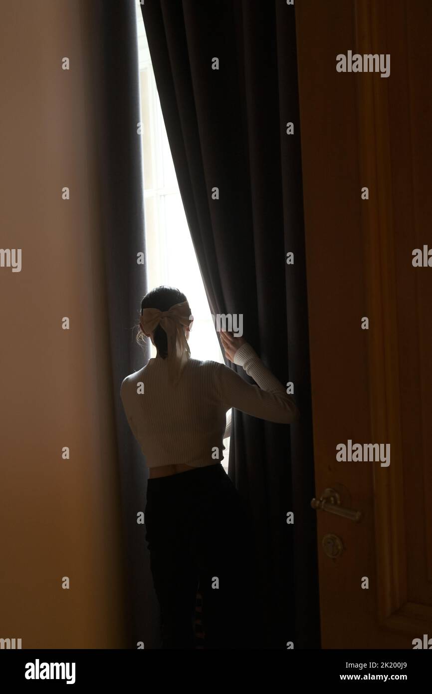 Junges Mädchen in einem klassischen weißen Pullover Blick auf das Fenster Stockfoto