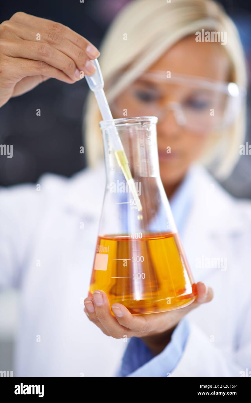 Das Experimentieren ist das Herz der Entdeckung. Ein Labortechniker hält einen Becher mit gelber Flüssigkeit hoch. Stockfoto