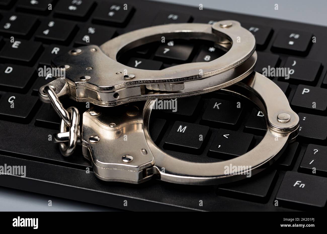 Computertastatur und Handschellen. Konzept für Cyberkriminalität, Internetsicherheit und Kriminalität. Stockfoto