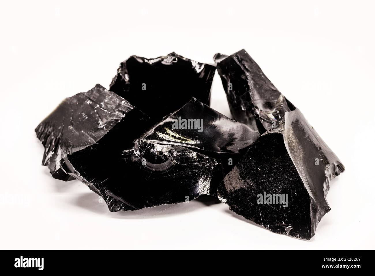Schwarzes Obsidian, schwarzes und kristallines Erz auf isoliertem weißem Hintergrund. Schwarzer Stein, therapeutisch, in der Meditation verwendet. Stockfoto