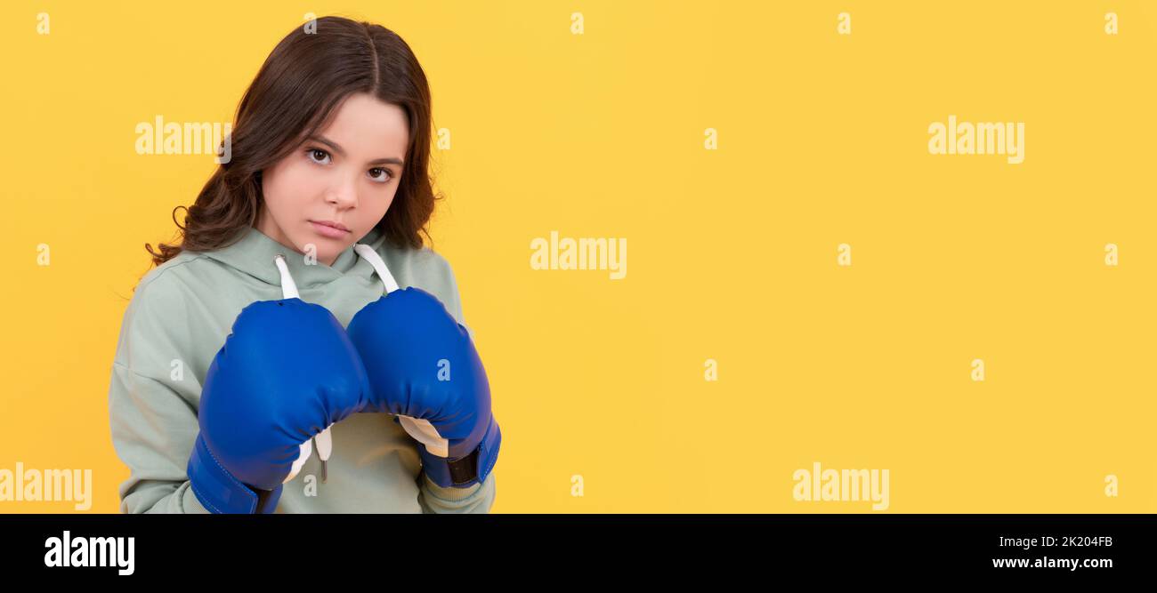 Ernsthaftes Kinderporträt in Boxhandschuhen auf gelbem Hintergrund. Horizontales Poster mit isoliertem Kindergesicht, Banner-Header, Kopierbereich. Stockfoto
