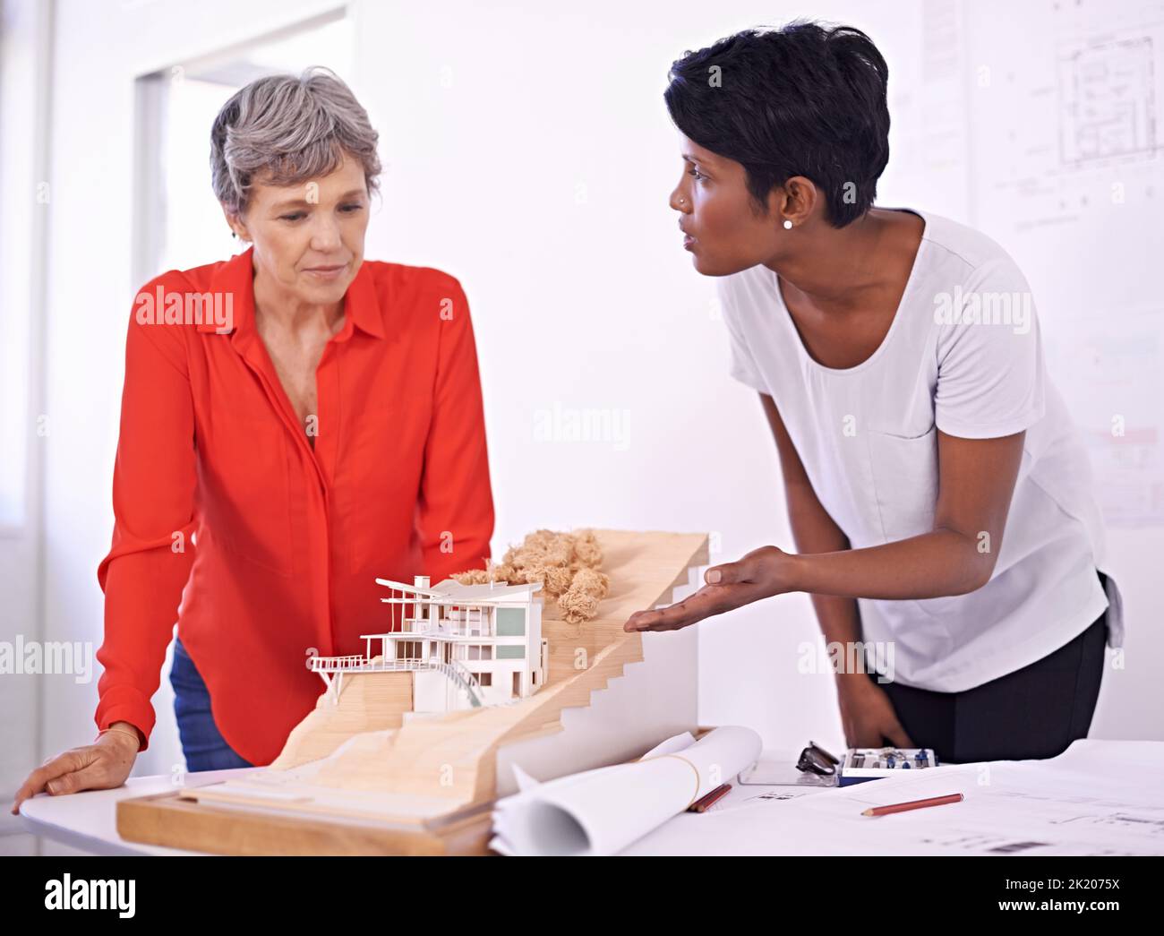 Glauben Sie, wir sollten Anpassungen vornehmen. Zwei weibliche Architekten diskutieren ein Architekturmodell. Stockfoto