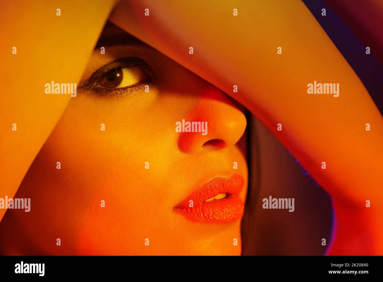 Farbenfrohe Pose. Studio-Porträt einer schönen jungen Frau mit künstlerischer Beleuchtung. Stockfoto