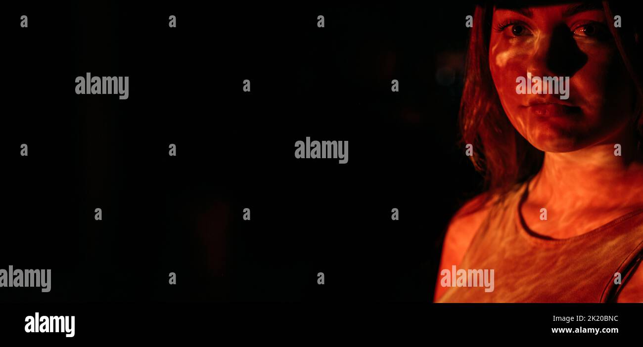Frauenrechte. Missbrauch von Beziehungen. Häusliche Gewalt. Feministische Bewegung. Porträt einer Aktivistin in hellrotem Projektionslicht isoliert auf dunklem CO Stockfoto