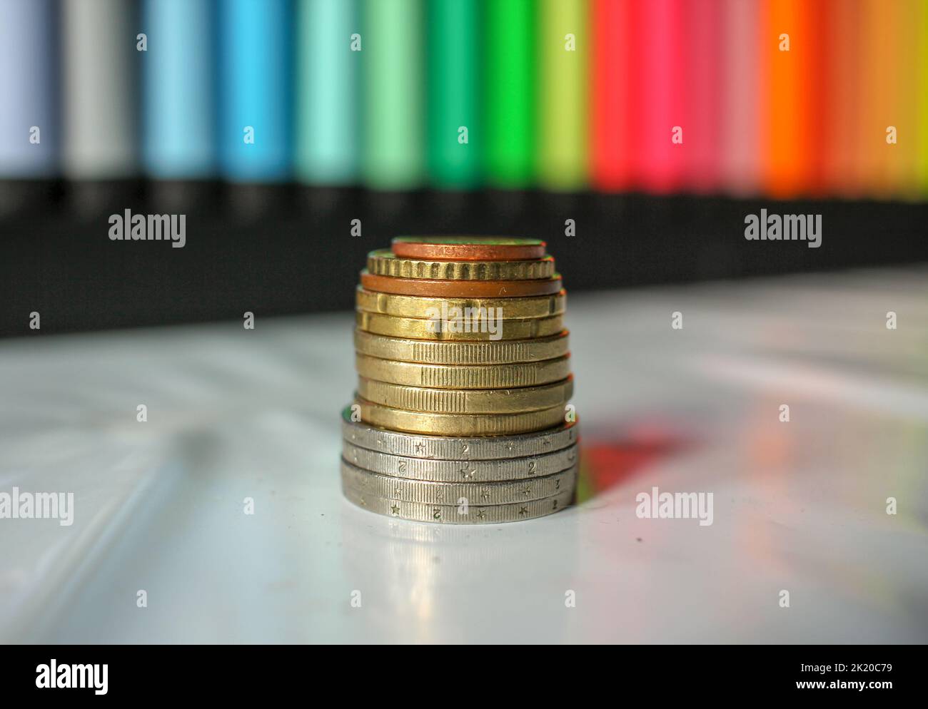 euro-Münzen in der Krise gestapelt, aber mit einem bunten Hintergrund Stockfoto