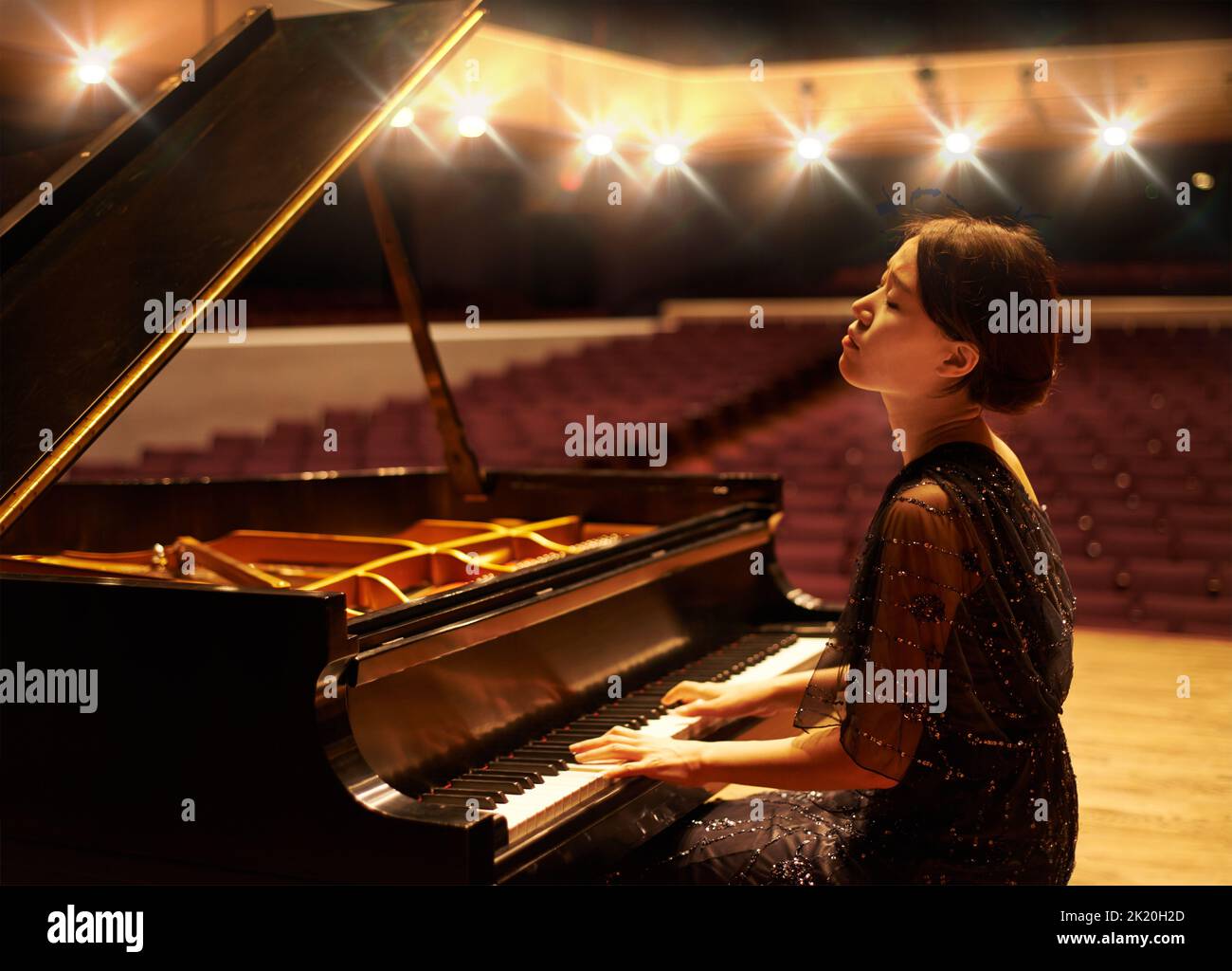 Musik ist eine Kunstform. Eine junge Frau, die während eines musikalischen Konzerts Klavier spielt. Stockfoto