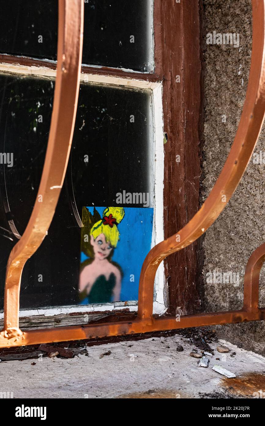 Bild einer jungen Frau auf einem Fenster hinter rostigen Metallstangen Stockfoto