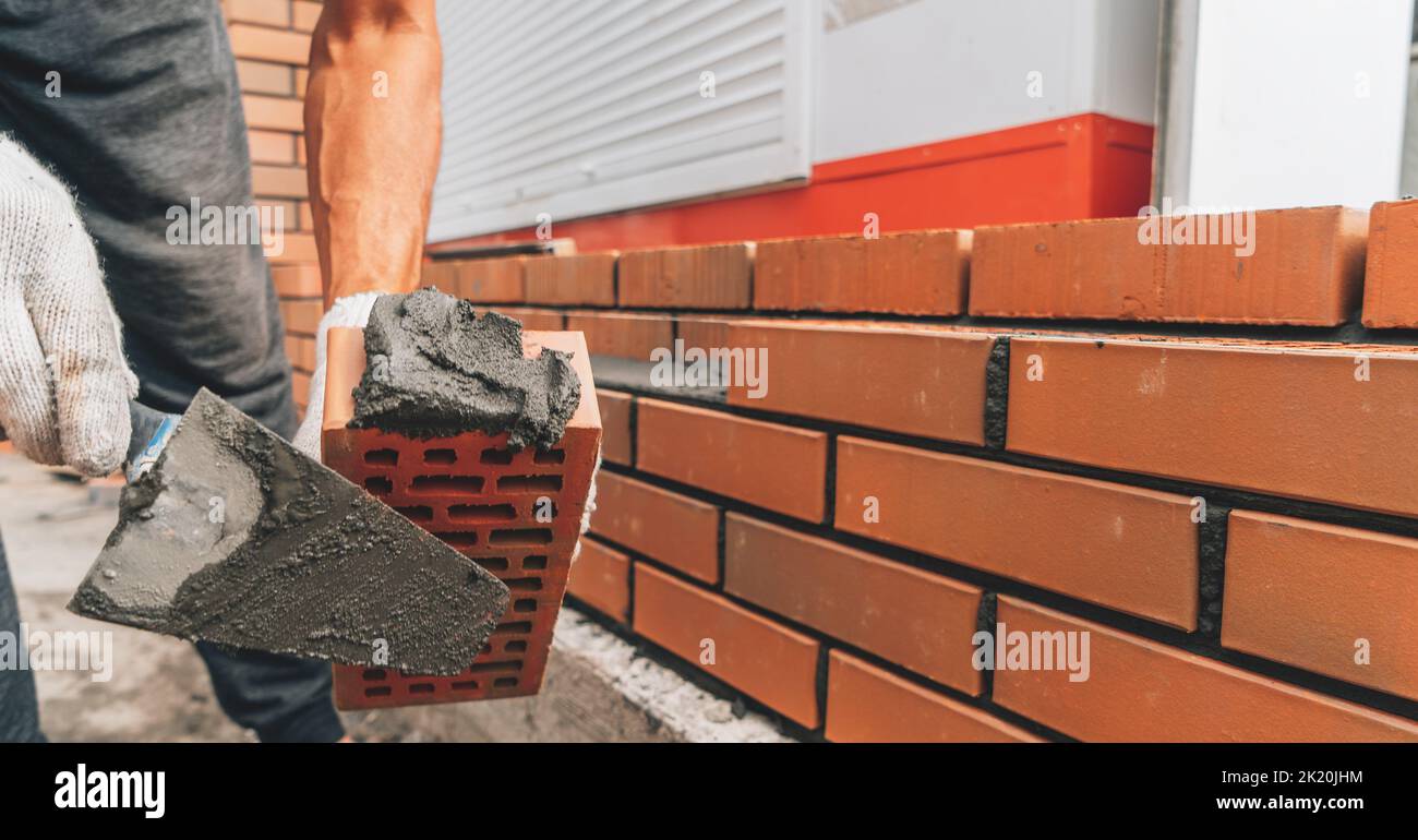Builder trägt Zementmörtel auf roten Ziegel Nahaufnahme. Ziegelbaukonzept. Stockfoto