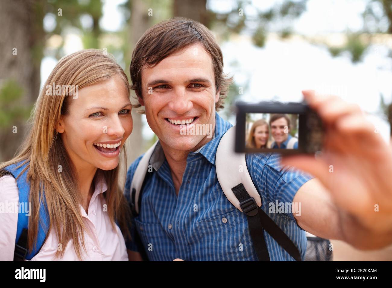 Erinnerungen festhalten. Das Paar schaute auf die Kamera und lächelte mit einem Mann, der ein Foto gemacht hat. Stockfoto