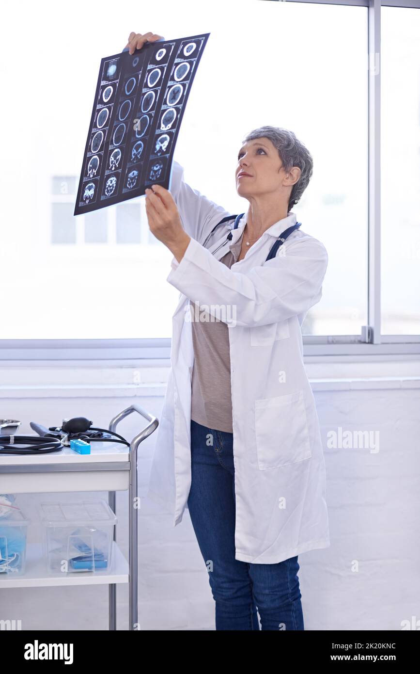 Zufrieden mit dem Ergebnis des CAT-Scans. Eine Ärztin, die Röntgenaufnahmen studiert. Stockfoto