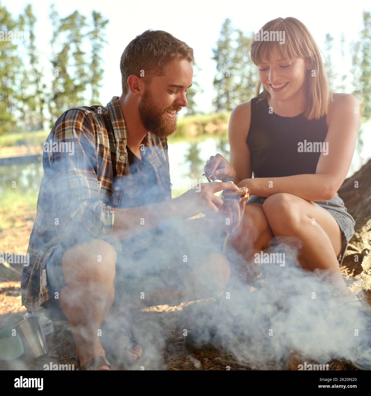 Diese bringen so viele Erinnerungen zurück... ein junges Paar, das beim Camping Smores macht. Stockfoto