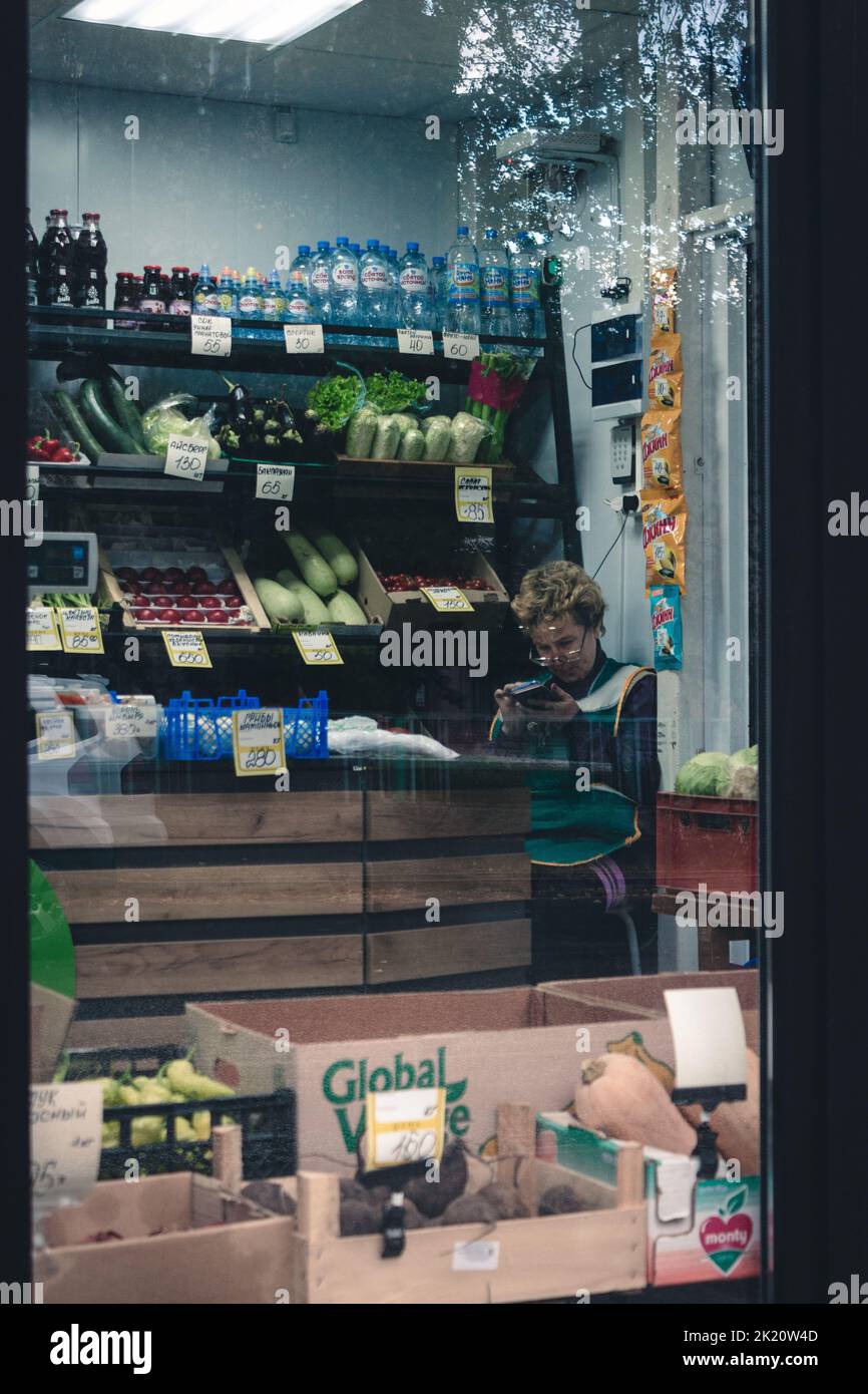 Eine vertikale Aufnahme einer älteren Verkäuferin, die in einem Lebensmittelgeschäft in Perm, Russland, sitzt Stockfoto