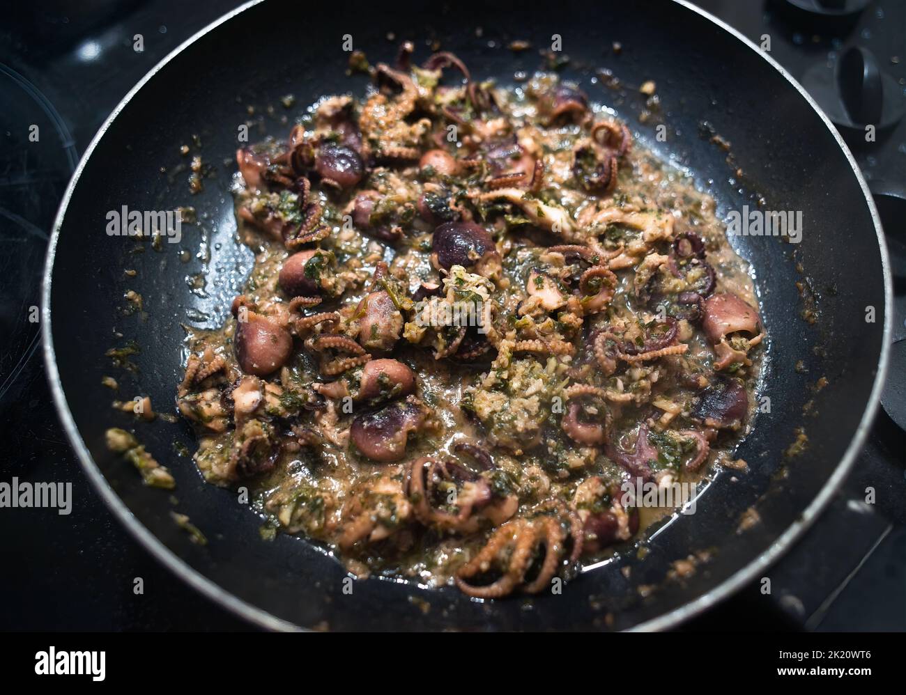 Gebratener kleiner Tintenfisch mit Knoblauch und Petersilie Stockfoto