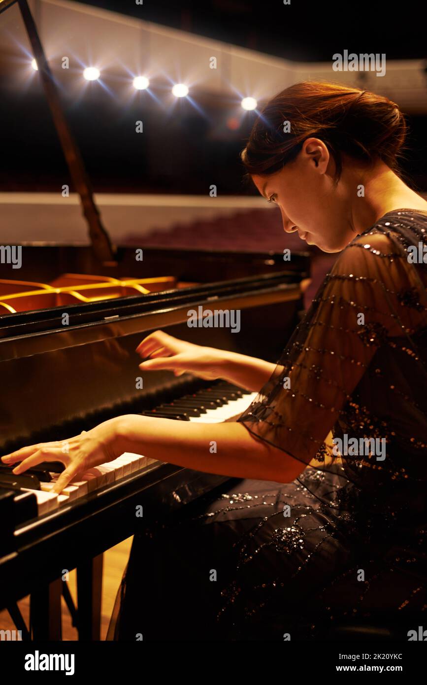 Eine junge Frau, die während eines musikalischen Konzerts Klavier spielt. Stockfoto