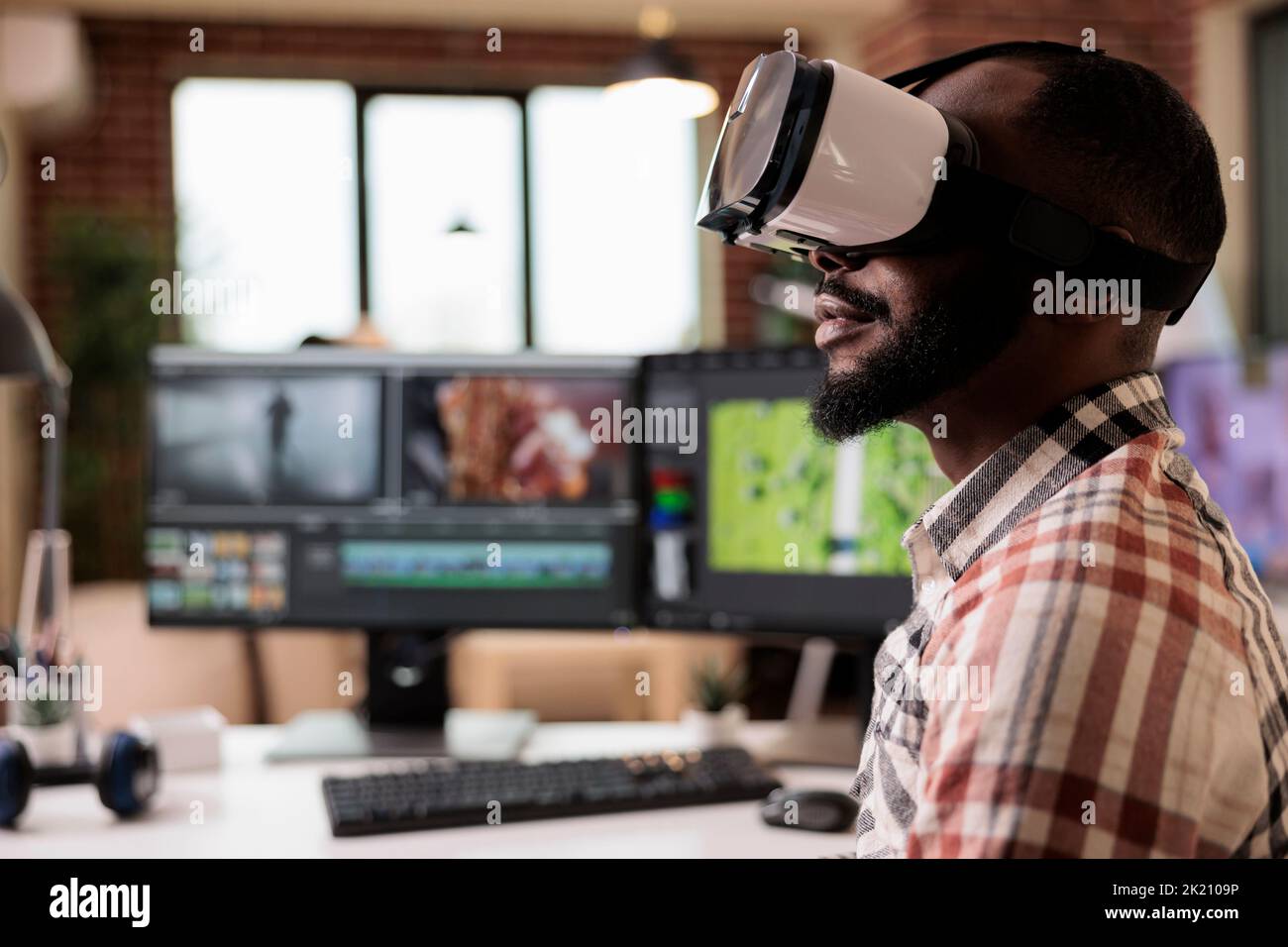 Männlicher Videofilmer, der Videos mit einer VR-Brille bearbeitet, an der Postproduktion mit Virtual-Reality-Headset und kreativer Software am Computer arbeitet. Inhaltsersteller, der Film oder Film macht. Stockfoto