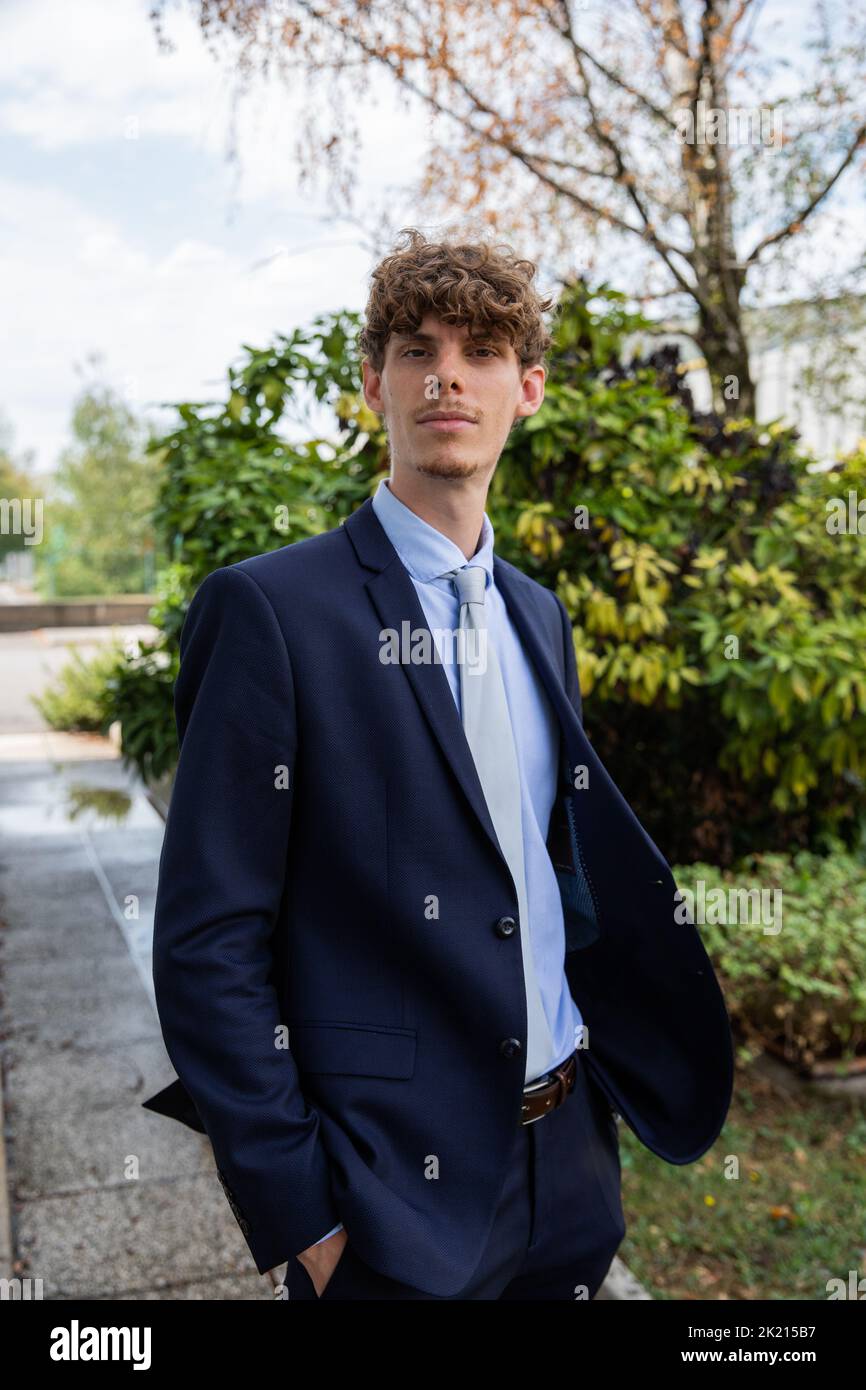 Eleganter Geschäftsmann im Garten mit den Händen in den Taschen. Erfolgreiche Person Stockfoto