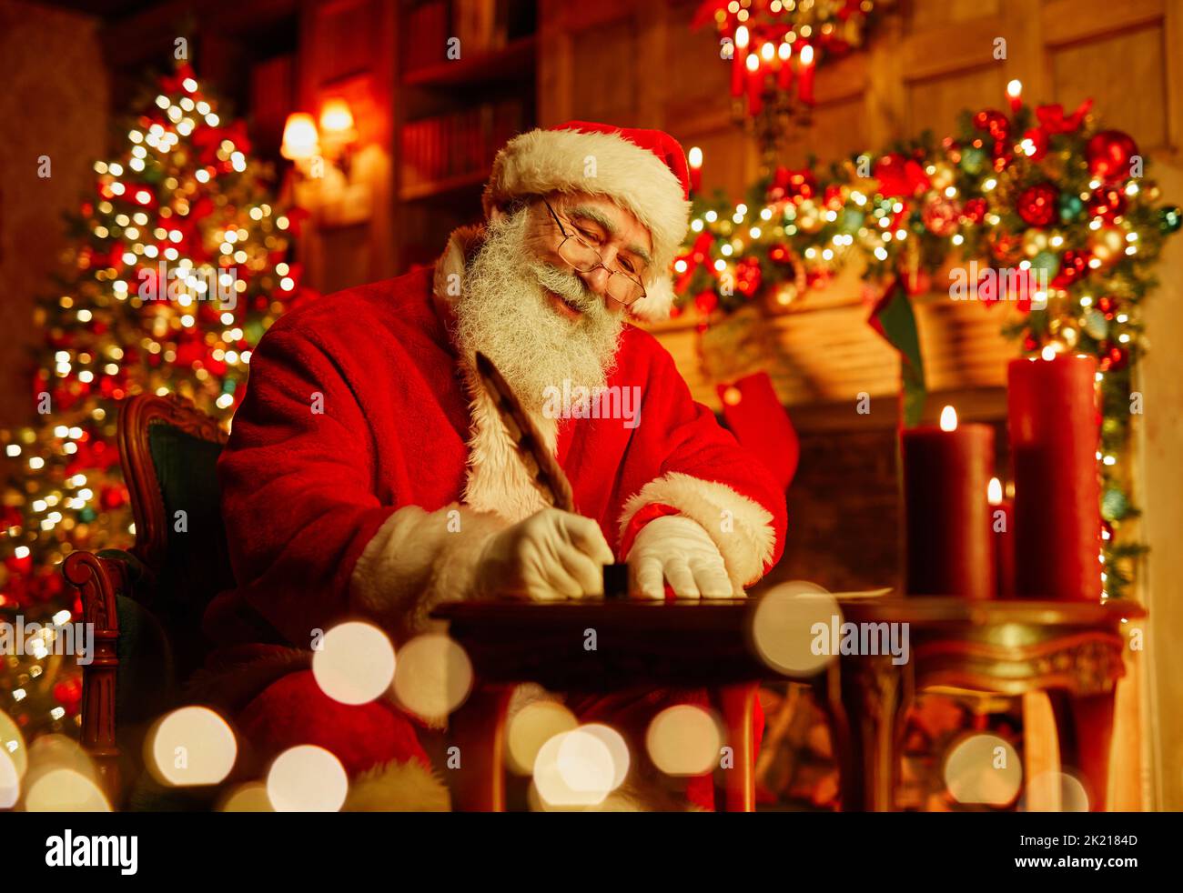Porträt des traditionellen Weihnachtsmanns Schreiben Brief von Kamin am Heiligabend und lächelnd, Kopierraum Stockfoto