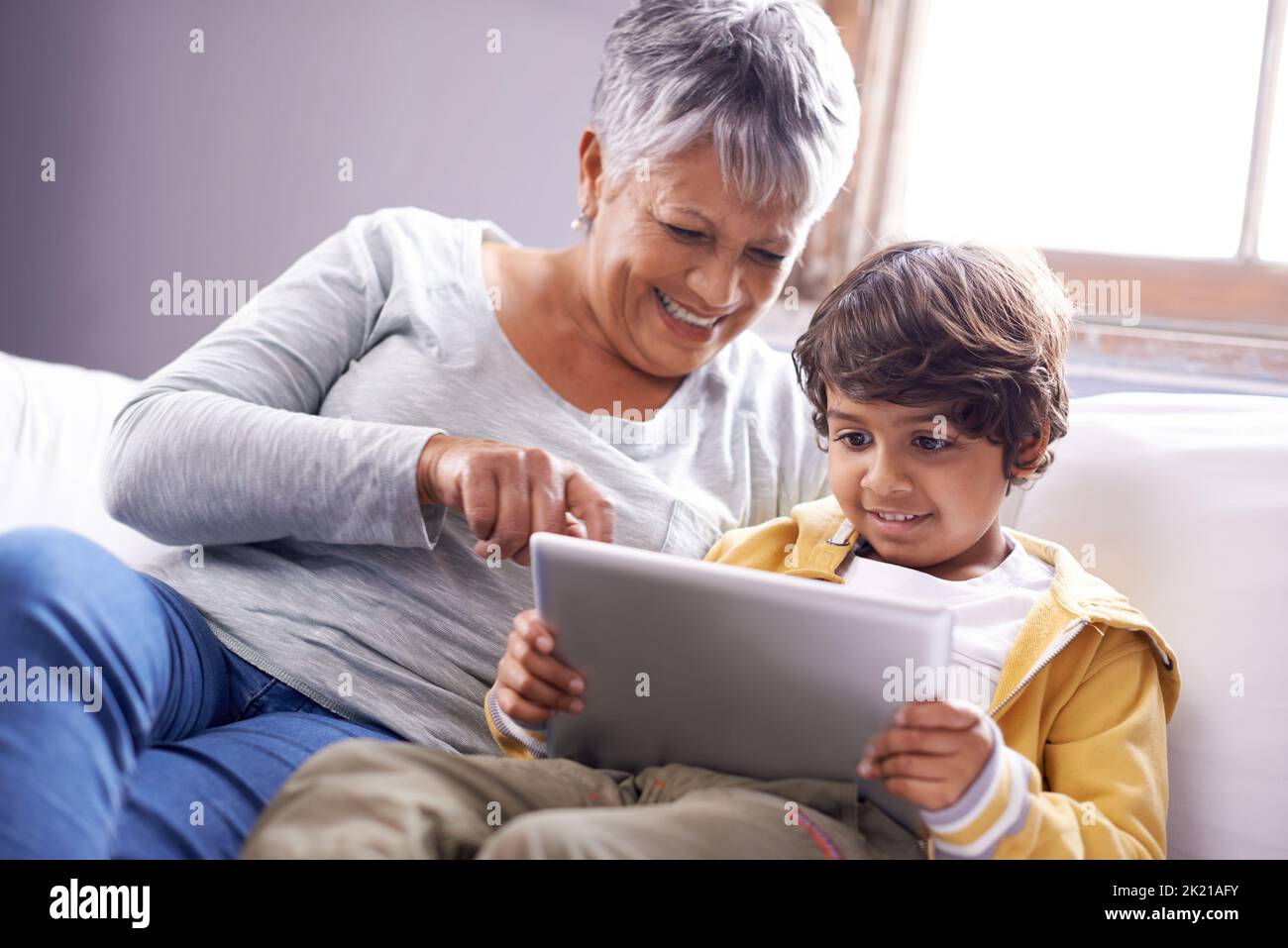 Zeigt ihrem Enkel ein paar Tricks online. Eine Großmutter und ein Enkel sitzen zu Hause mit einem digitalen Tablet zusammen. Stockfoto