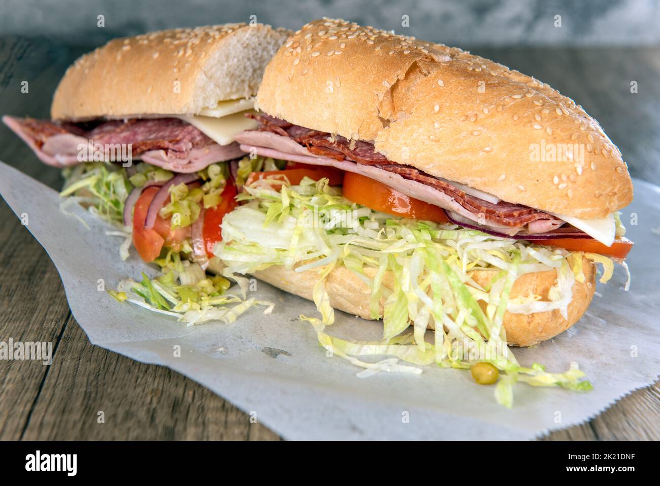 Das Mittagessen wird mit einem geladenen italienischen Sub-Sandwich serviert, das mit Fleisch, Gemüse und Rosensalat überfüllt ist. Stockfoto