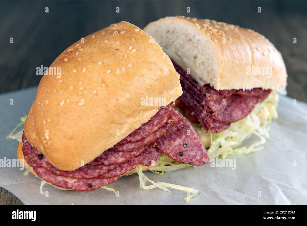 Das Mittagessen wird mit einem geladenen Salami-Sandwich serviert, das mit Rosensalat überfüllt ist. Stockfoto