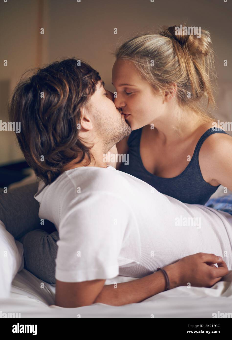 Aufwachen mit einem Kuss. Ein liebevolles junges Paar küsst sich im Bett. Stockfoto