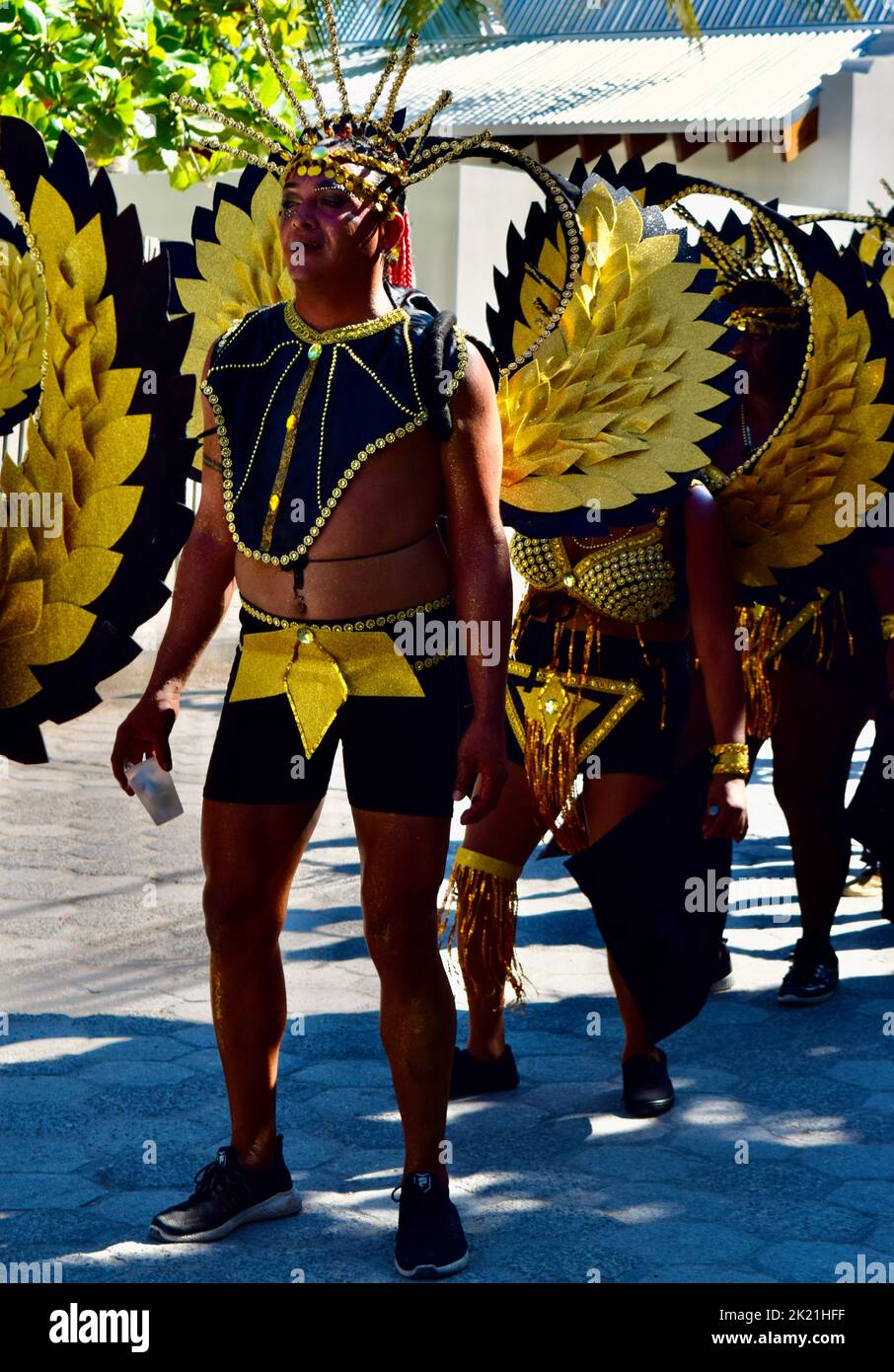 Ein belizischer Mann, der ein glänzendes, geflügeltes, schwarz-gelbes Kostüm trägt, tanzt in der Parade zum Karneval 2022 in San Pedro, Belize. Stockfoto