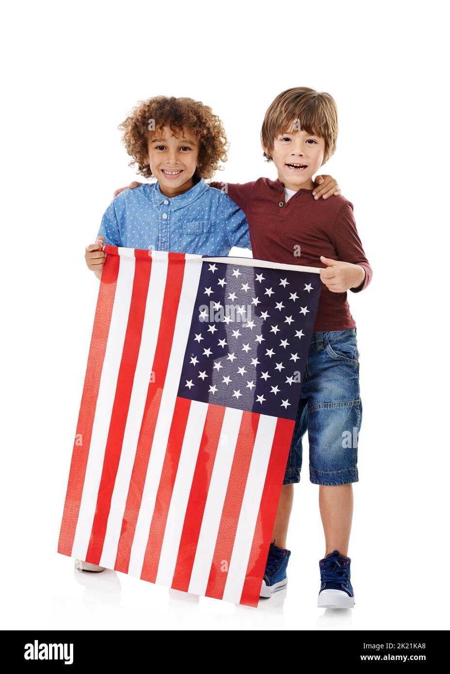 Stolz darauf, Amerikaner zu sein. Studioaufnahme von zwei niedlichen kleinen Jungen, die die amerikanische Flagge vor einem weißen Hintergrund zusammenhalten. Stockfoto