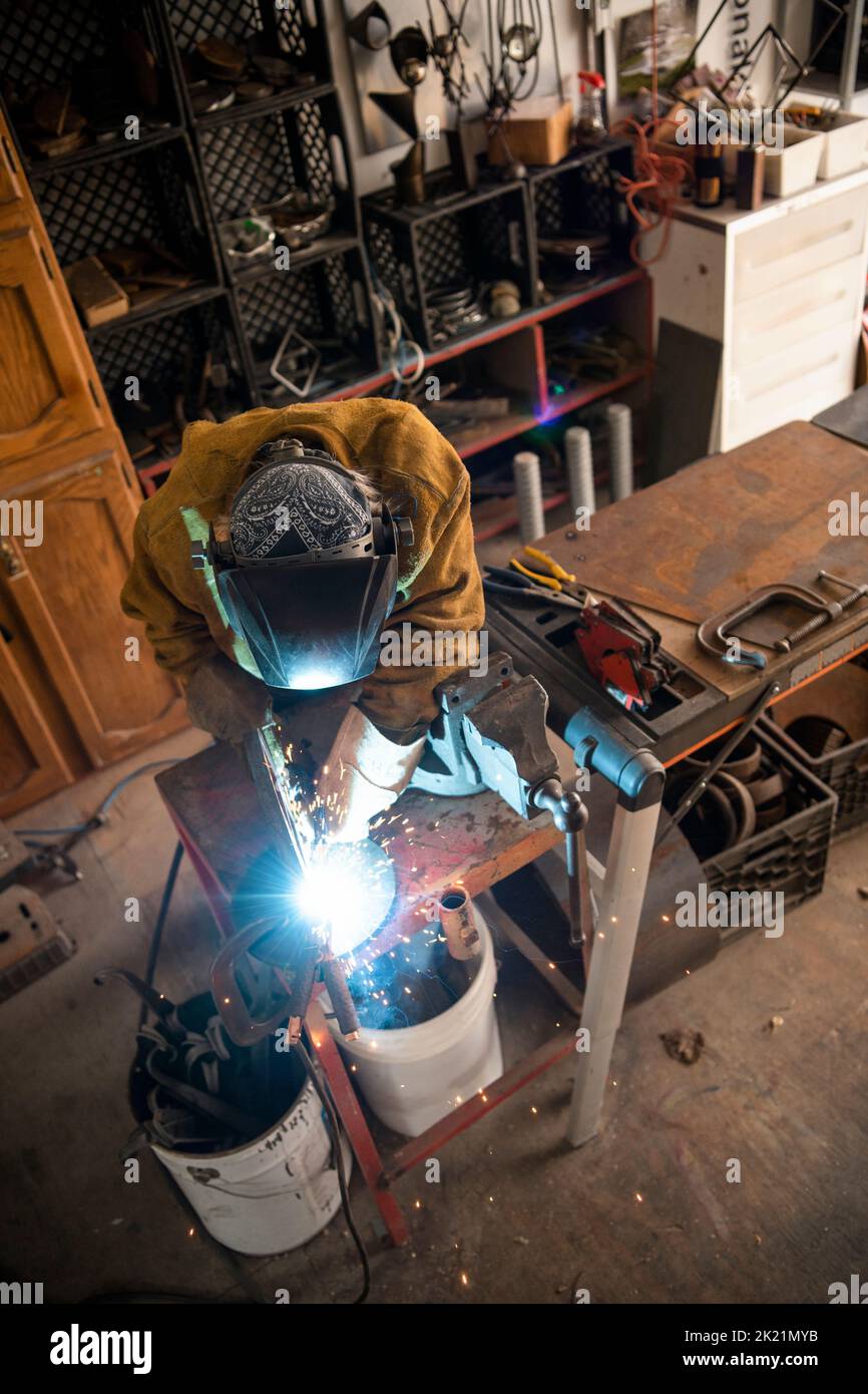 Bildhauerin, die Schweißbrenner an der Werkbank in der Werkstatt verwendet Stockfoto