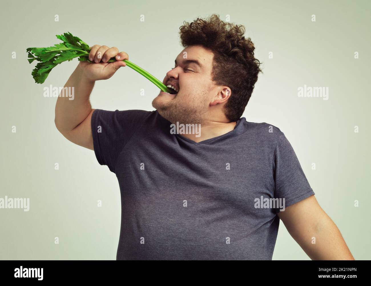 Ist das, wie Sie es essen. Ein übergewichtiger Mann beißt in einen Sellerie-Stick. Stockfoto