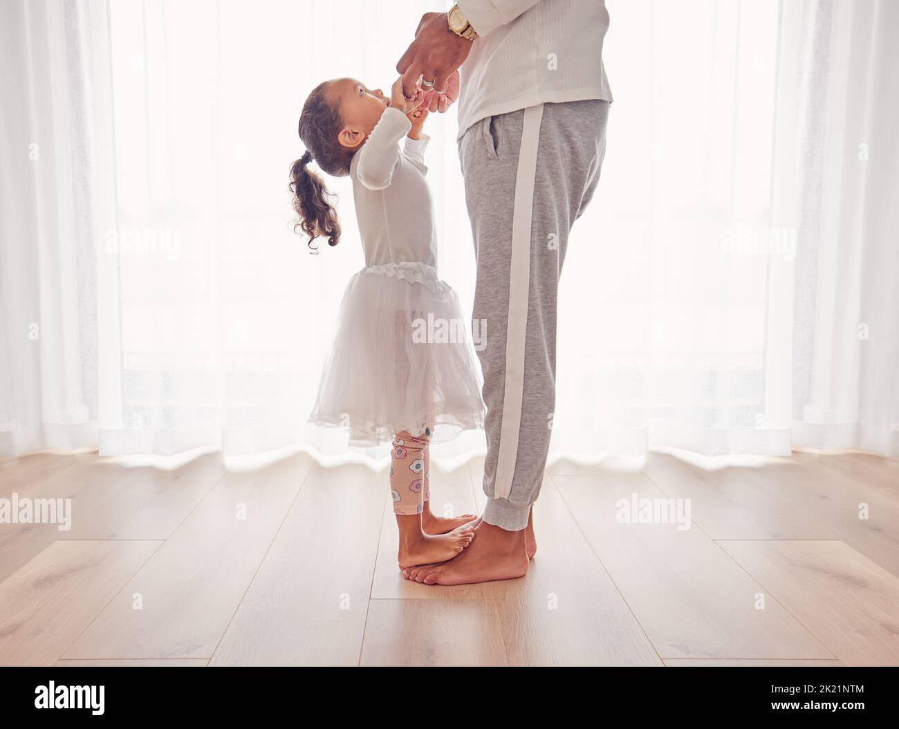 Familie, Tanz und Tochter auf Papa Füße zusammen auf dem Boden des Innenraums für Glück, Kindheit und Bindung. Pflege, Liebe und Jugend mit Vater tanzen Stockfoto