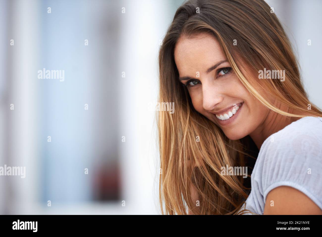 Machen Sie Ihre eigene Art von Glück. Porträt einer schönen jungen Frau, die vor der Kamera lächelt, während sie draußen sitzt. Stockfoto