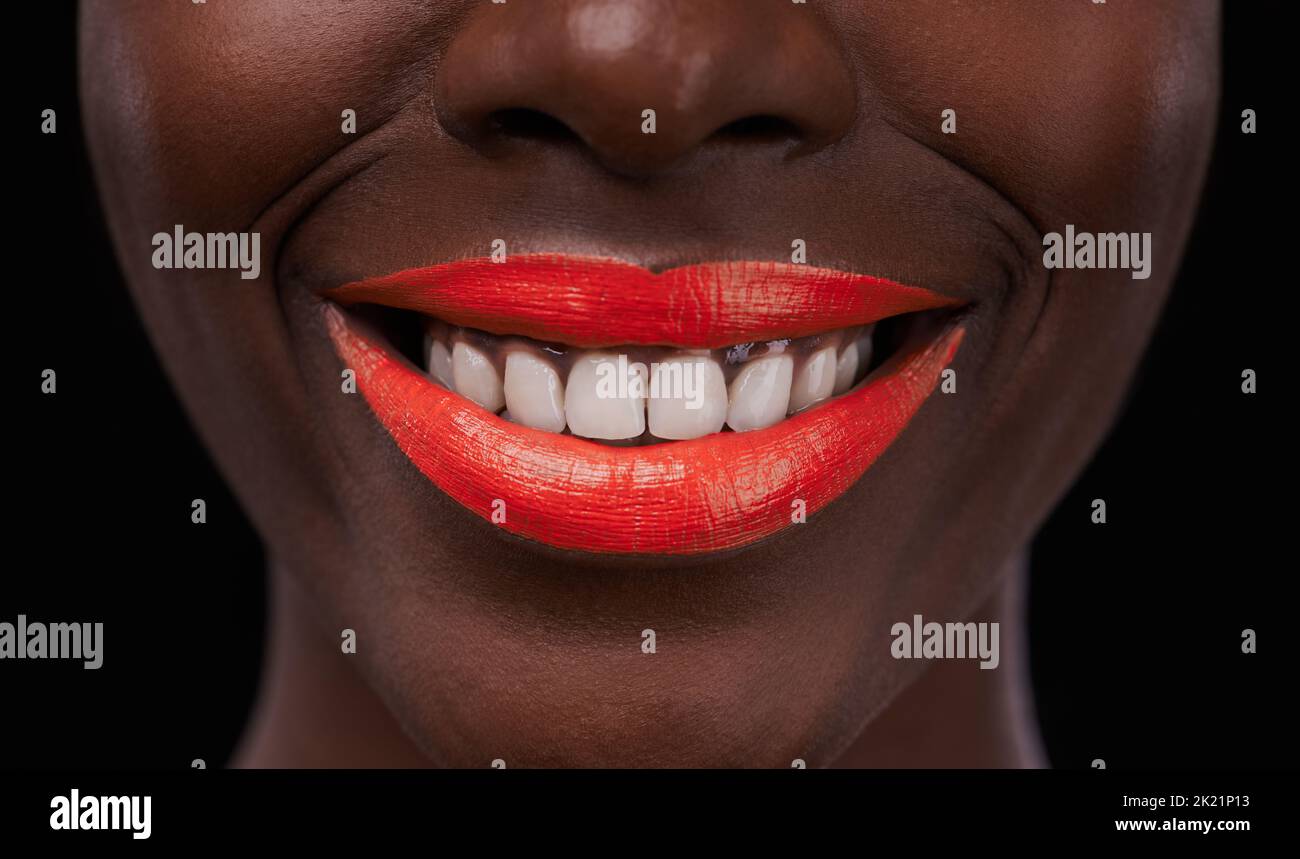 Das Lächeln zeigt sich. Beschnittene Ansicht einer afrikanischen Frau mit leuchtend roten Lippen auf schwarzem Hintergrund. Stockfoto