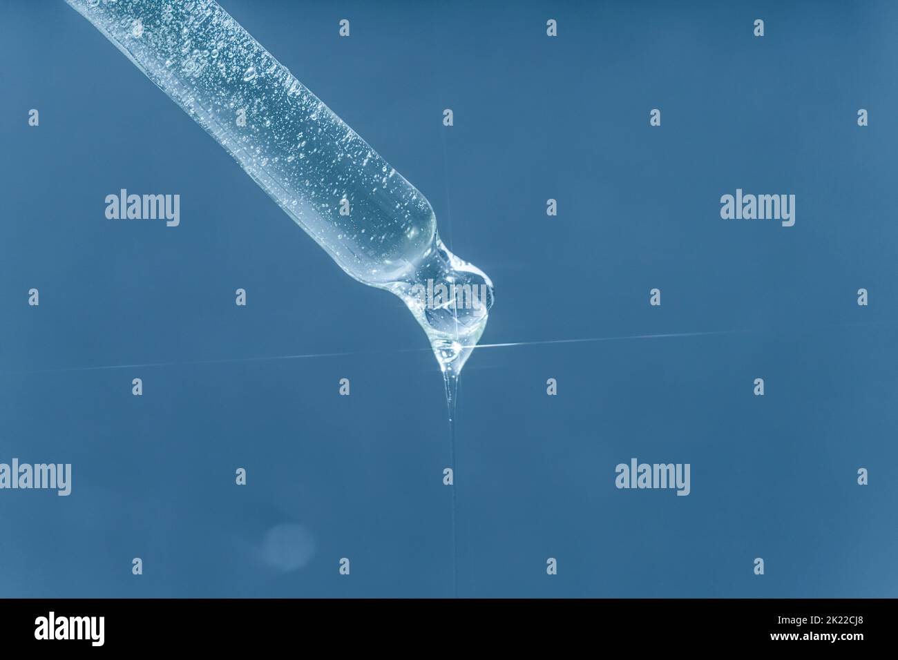 Ein Tropfen feuchtigkeitsspendendes Serum aus einer Pipette. Auf blauem Hintergrund. Stockfoto