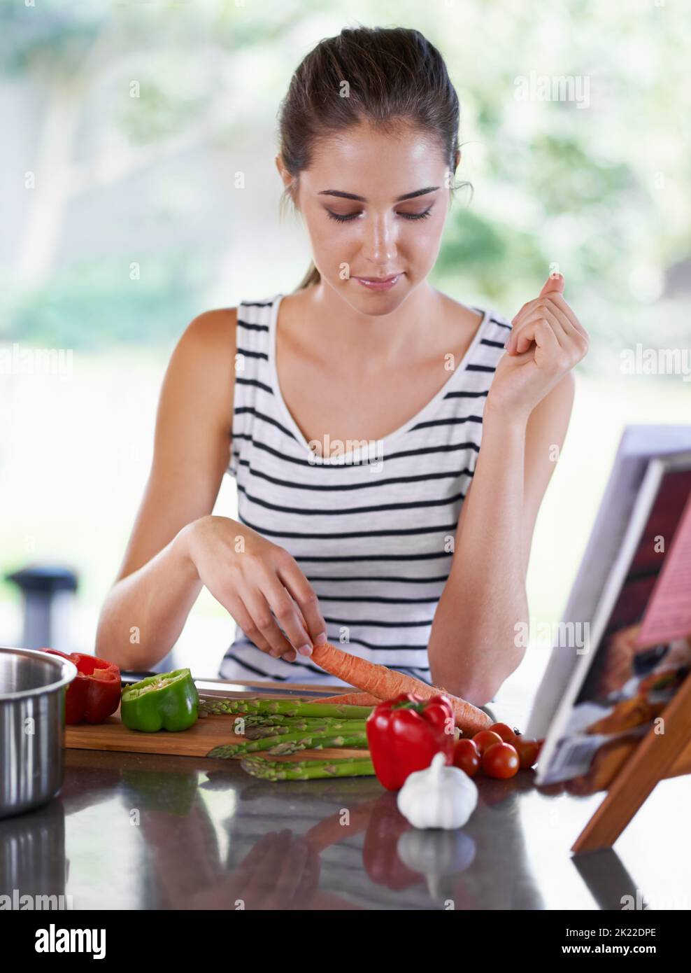 Ein gesundes Leben führen. Eine junge Frau, die aus einem Rezeptbuch kocht. Stockfoto