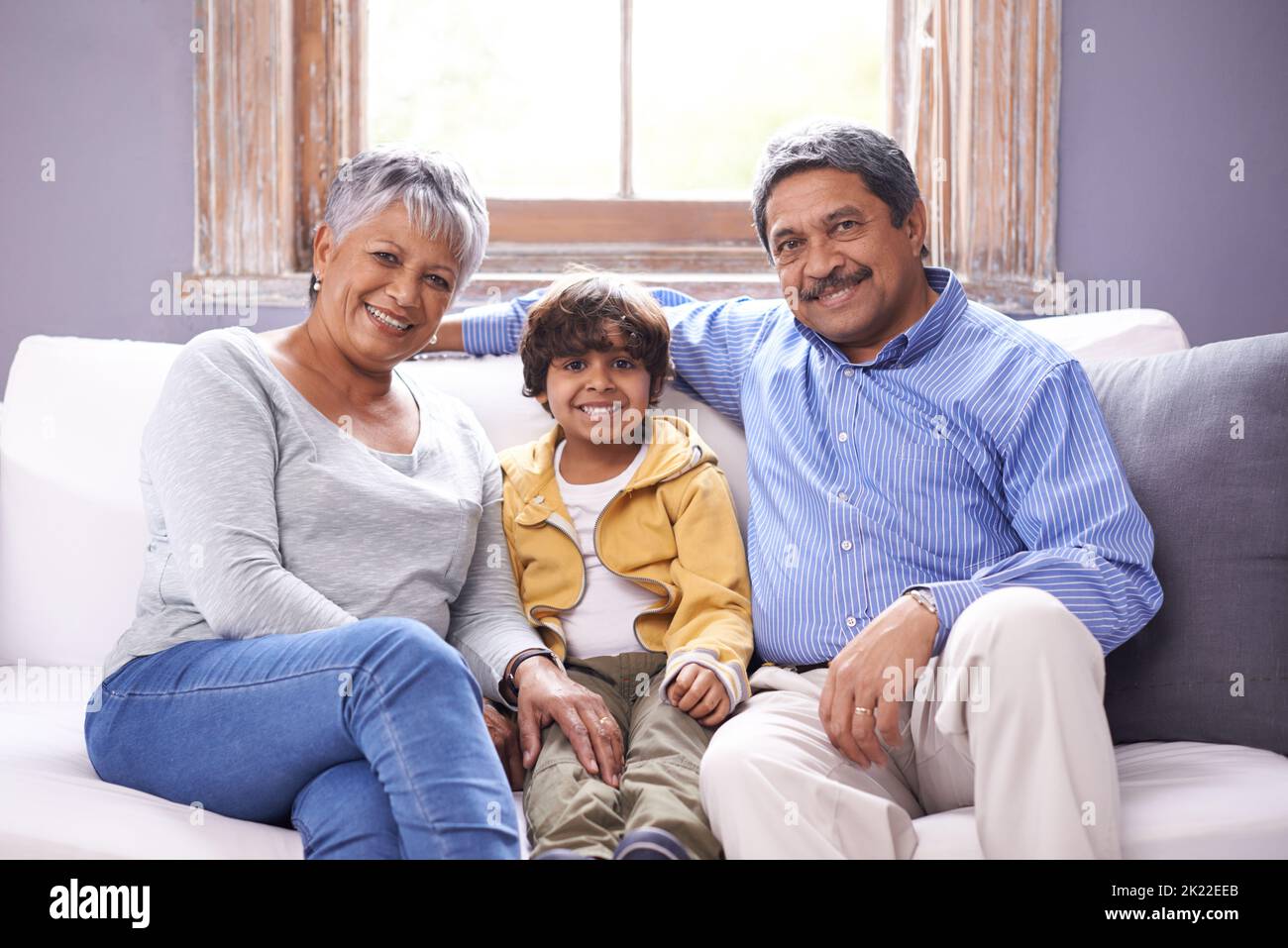 Sie sind die besten Großeltern. Zwei Großeltern sitzen mit ihrem Enkel auf einer Couch. Stockfoto