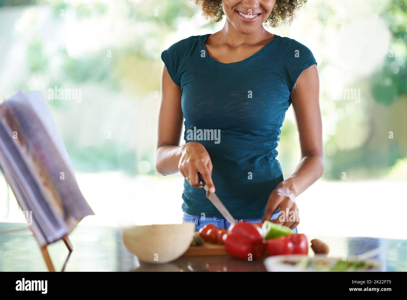 Ein köstliches Gericht in der Küche zubereiten. Eine junge Frau, die aus einem Rezeptbuch kocht. Stockfoto