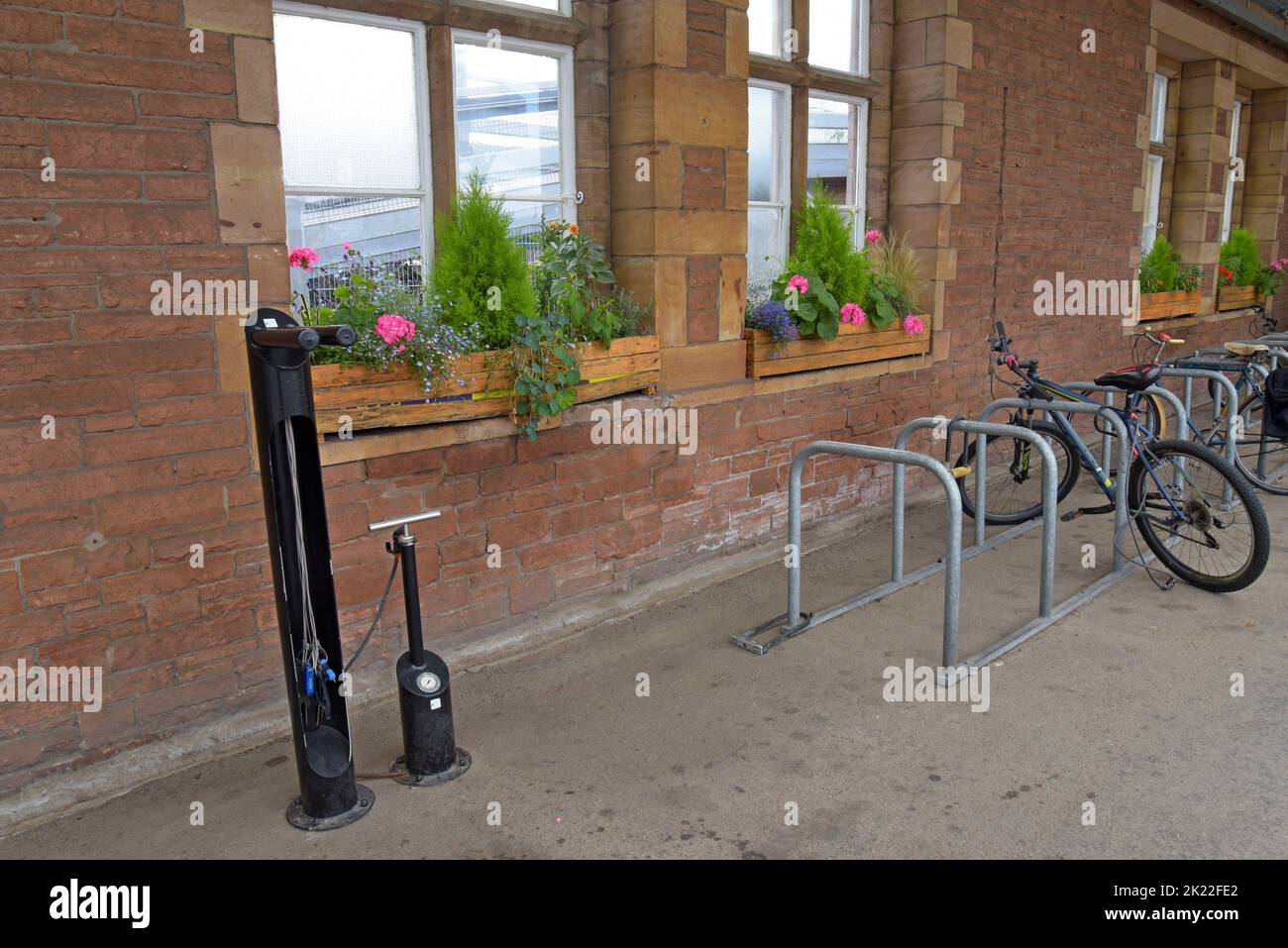 Ein Fahrradparkplatz mit öffentlichen Reparaturwerkzeugen und Fahrradreifenpumpe am Bahnhof Penrith, Cumbria, Großbritannien, August 2022 Stockfoto