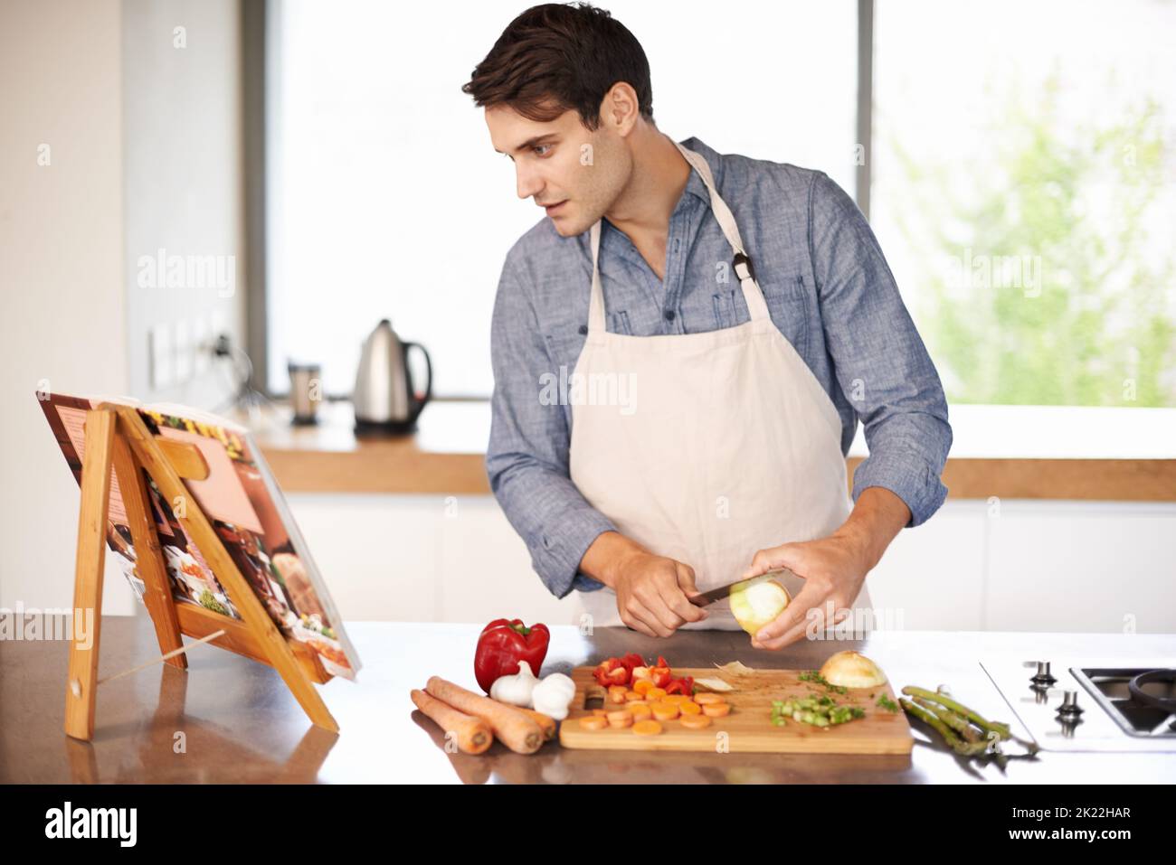 Ich habe hier nichts über das Weinen gelesen, ein Mann, der eine Mahlzeit aus einem Rezeptbuch zubereitet. Stockfoto