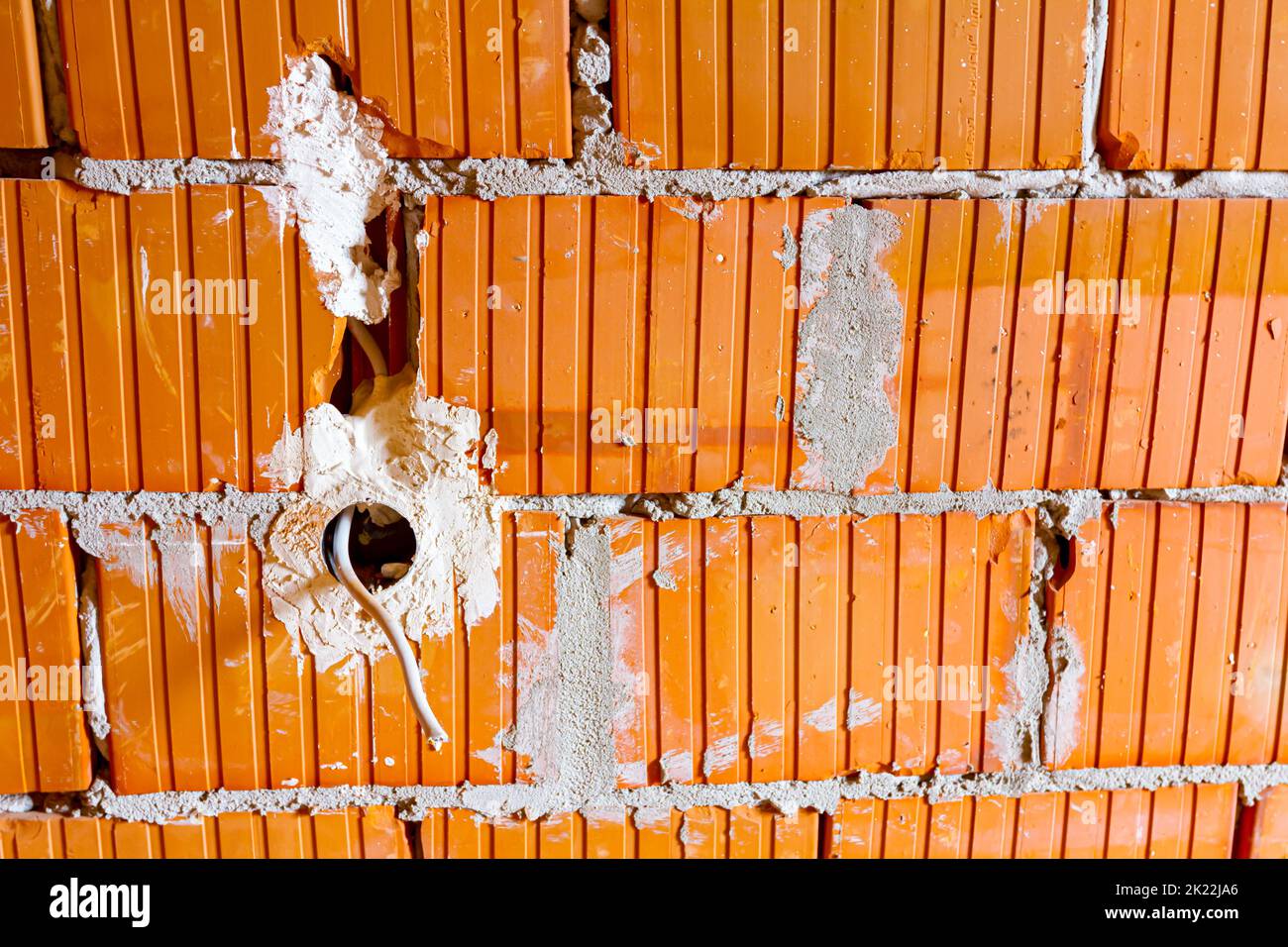 Eine freiliegende Steckdose mit entfernter oberer Abdeckung für die Installation der Verkabelung an der Wand mit im Bau befindlichen Gebäudeblöcken. Stockfoto