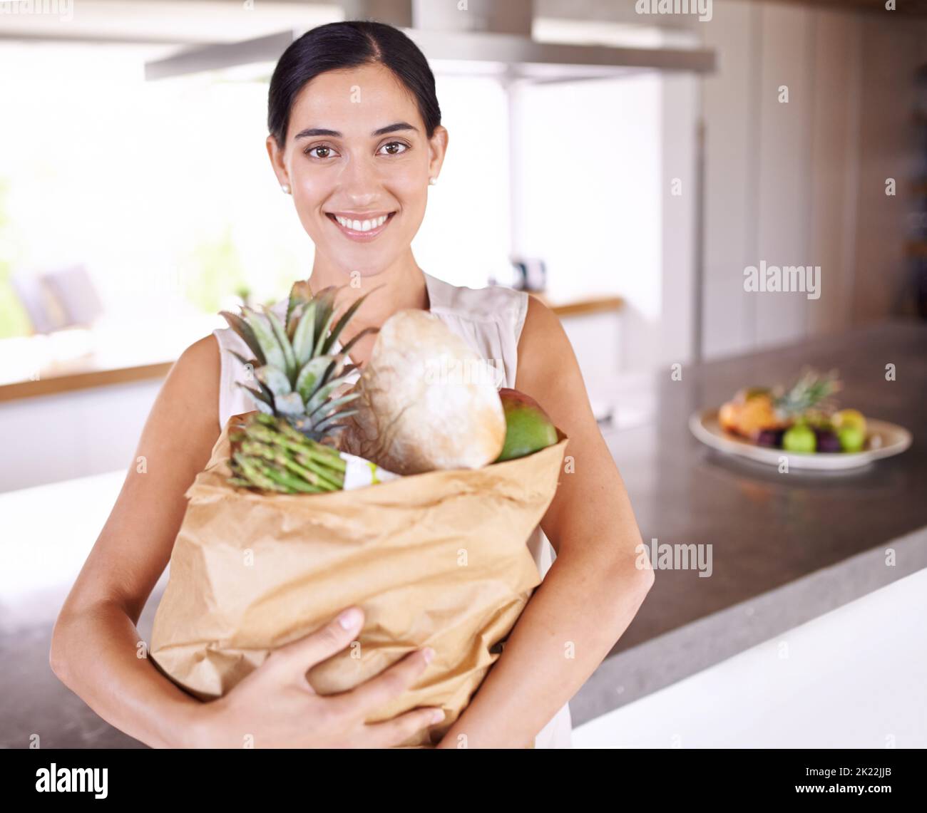 In große Gesundheit investieren. Eine attraktive Frau, die eine Tüte Lebensmittel in ihrer Küche hält. Stockfoto