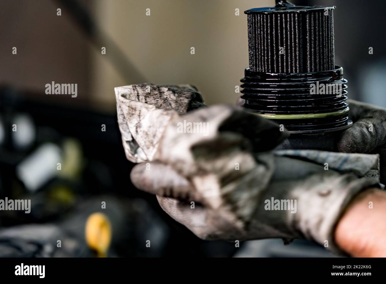 Hände eines Reparaturwerkers, der einen verschmutzten Autoölfilter hält Stockfoto