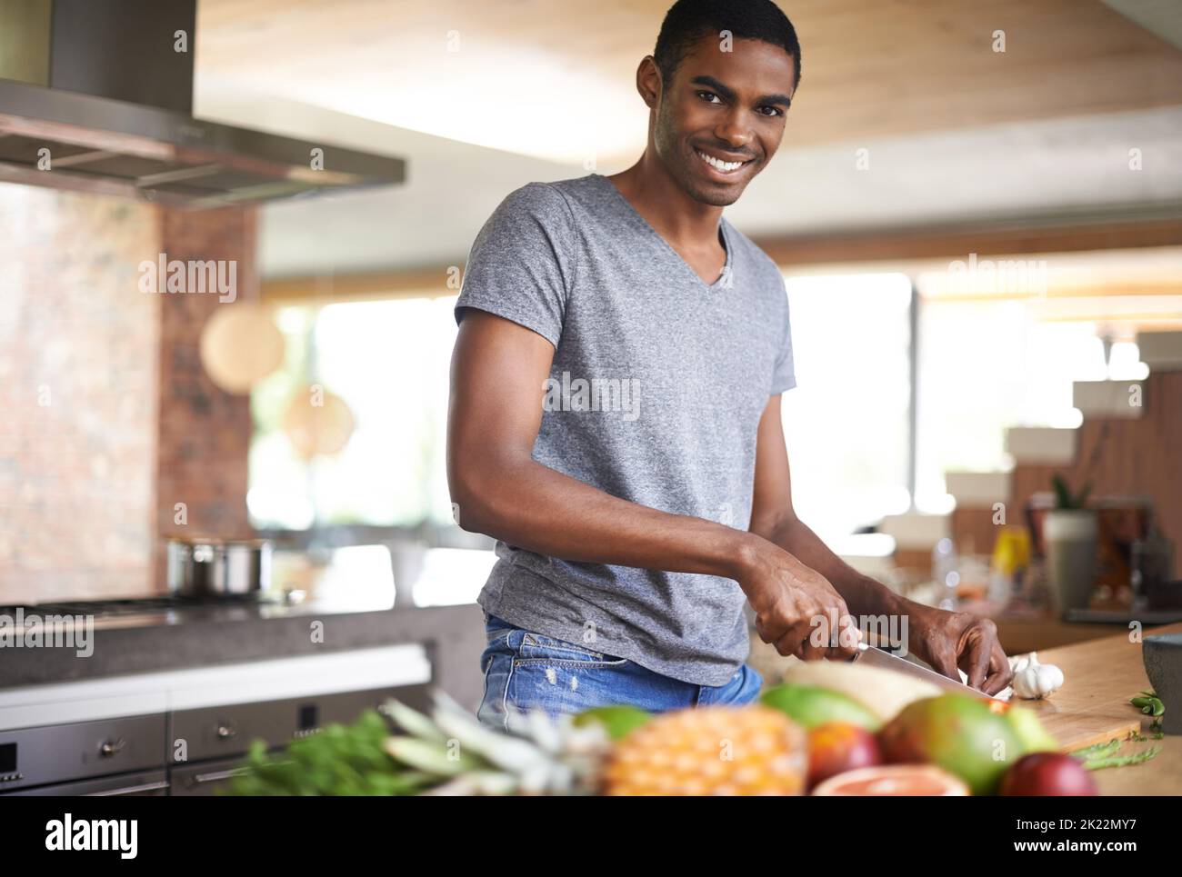 Hes ein feiner Zerkleinerer. Ein hübscher ethnischer Mann, der Gemüse im Haus zubereitet. Stockfoto