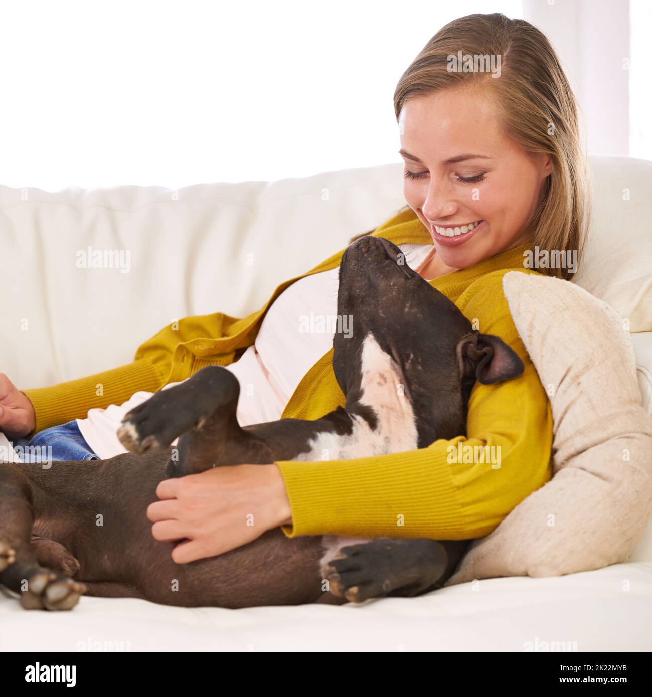 Hes ist die treueste Freundin, die man sich nur wünschen kann. Eine attraktive junge Frau streichelst ihren Hund auf dem Sofa. Stockfoto