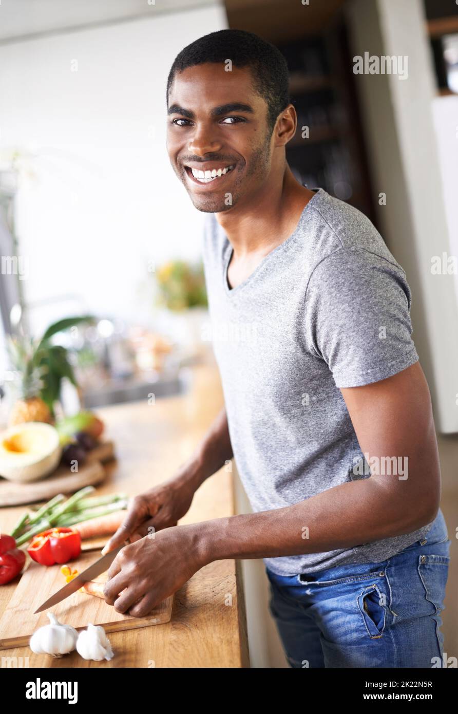 Hes ein Mann mit vielen Talenten. Ein hübscher ethnischer Mann, der Gemüse in Innenräumen zubereitet. Stockfoto