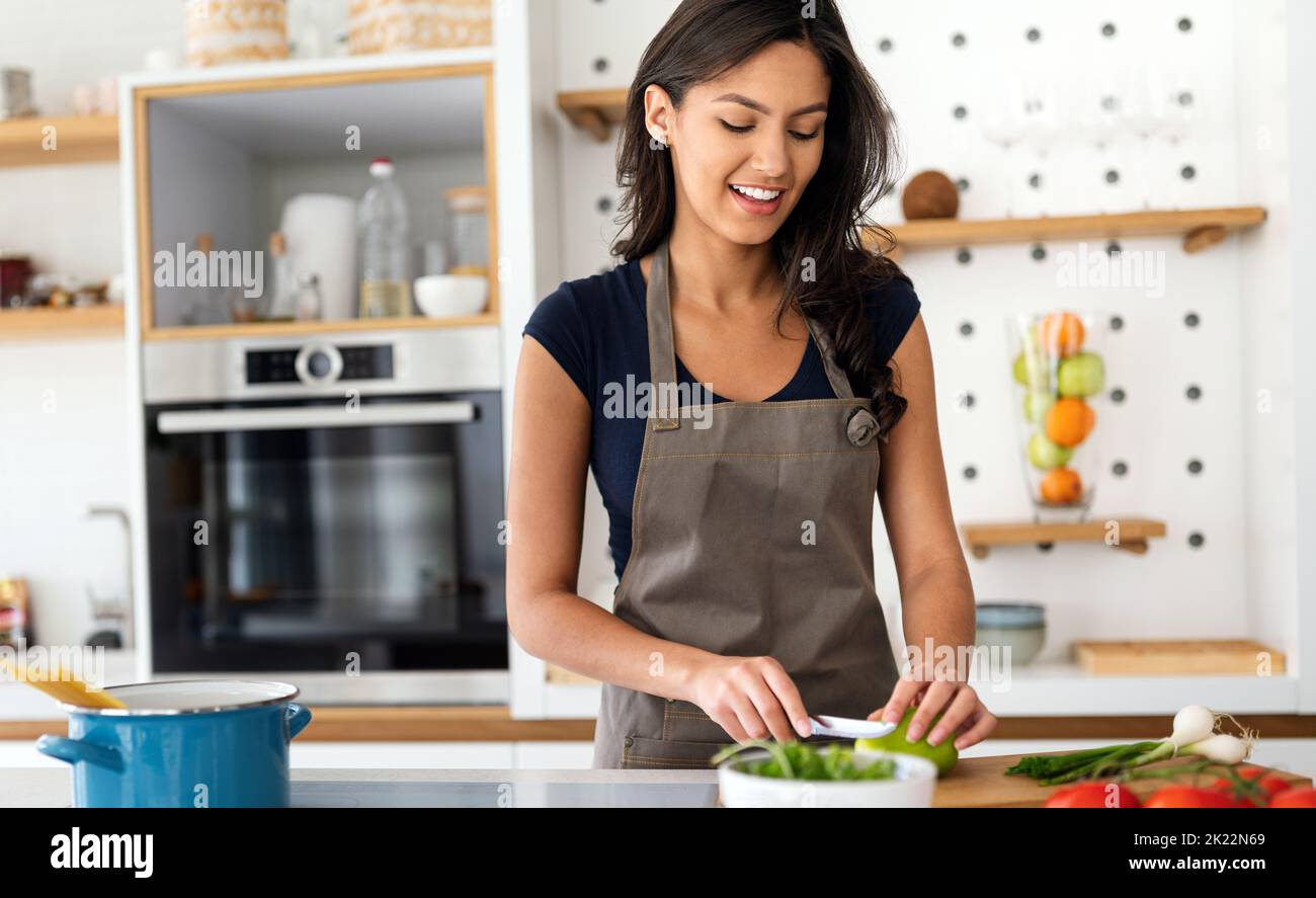 Frau macht Salat in der Küche lächelnd und lacht glücklich und fröhlich. Stockfoto