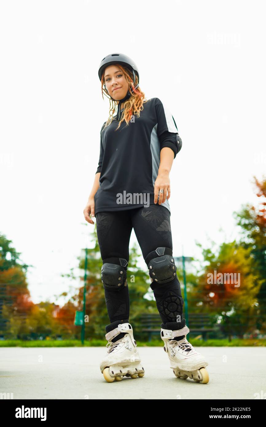 Junge aktive Frau in Rollerklingen mit Helm Stockfoto