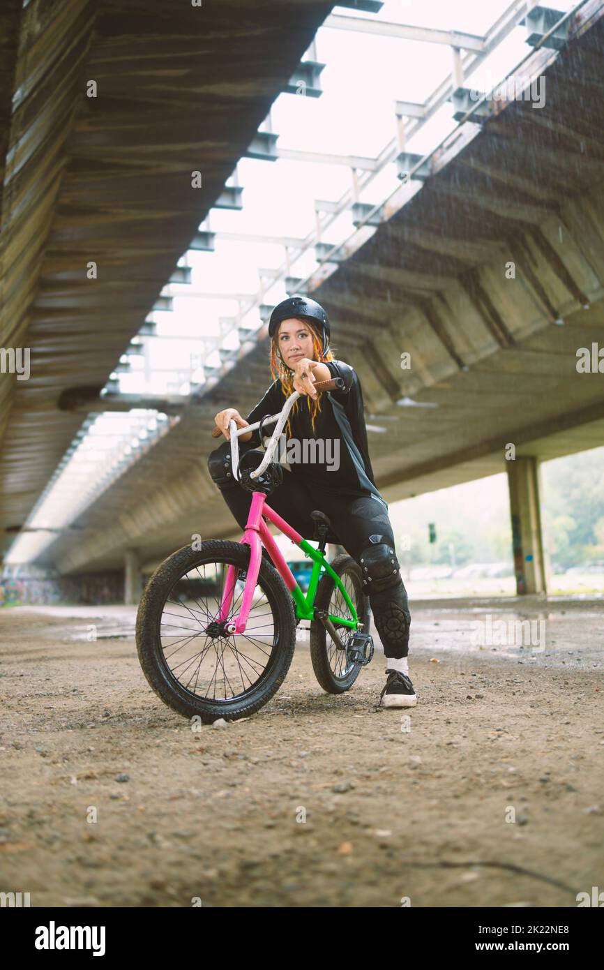 Junge aktive Frau, die mit Helm auf dem Freestyle-Bike sitzt Stockfoto