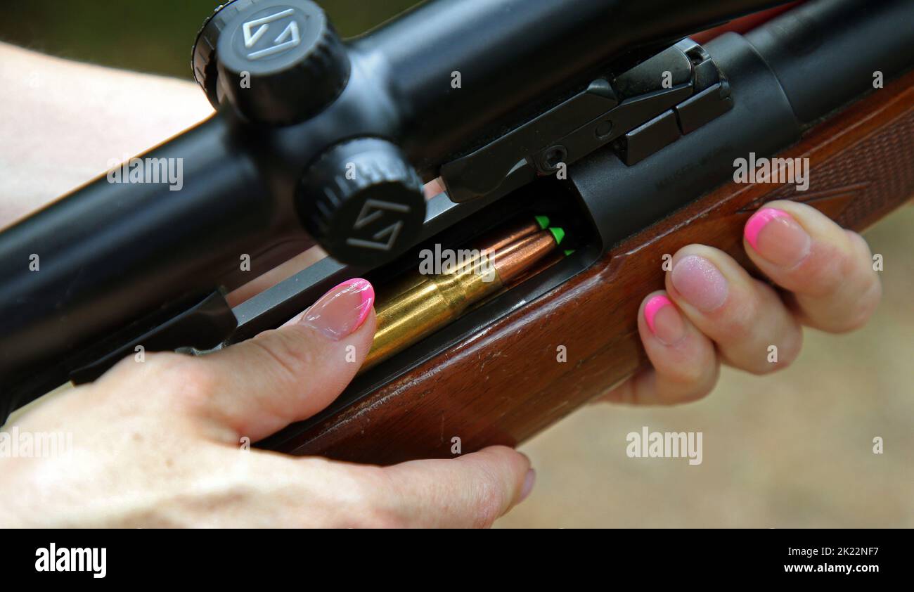 Spreenhagen, Deutschland. 16. August 2022. Eine Jägerin steht in einem Waldgebiet und lädt ihr Jagdgewehr mit bleifreier Jagdmunition. Immer mehr Frauen nehmen an der Jägerprüfung, dem sogenannten Green Baccalaureate, Teil und widmen sich der Pflege und Pflege der Natur. Quelle: Wolfgang Kumm/dpa/Alamy Live News Stockfoto